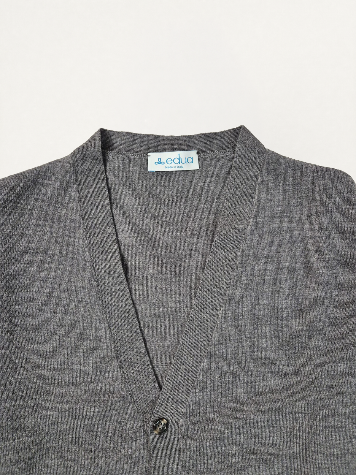 Dettaglio dello scollo a V e del logo Edua del cardigan uomo in lana merino colore grigio melange