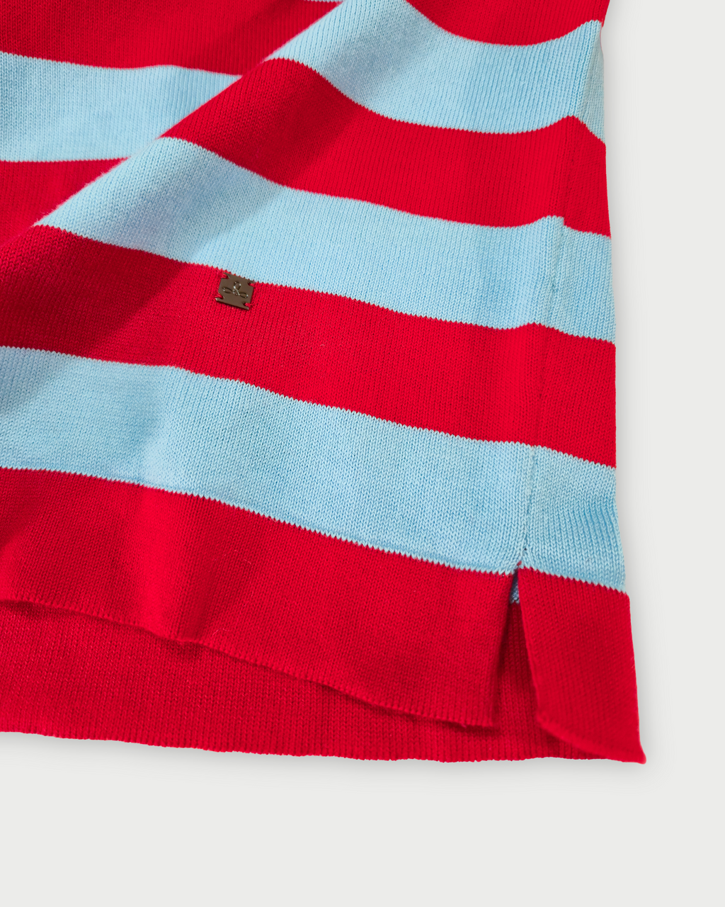 Dettaglio fondo con spacchetto e logo Edua maglia donna in cotone a righe rosse e celesti su sfondo bianco