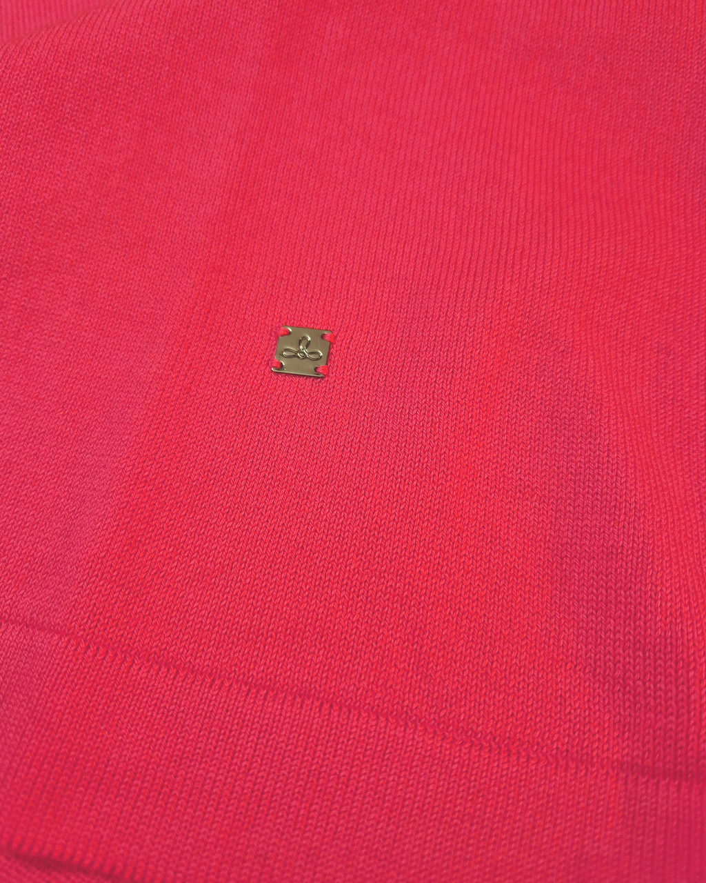 Dettaglio del logo Edua della maglia donna in maglia di cotone rosa corallo con girocollo e profili bianchi sulle maniche