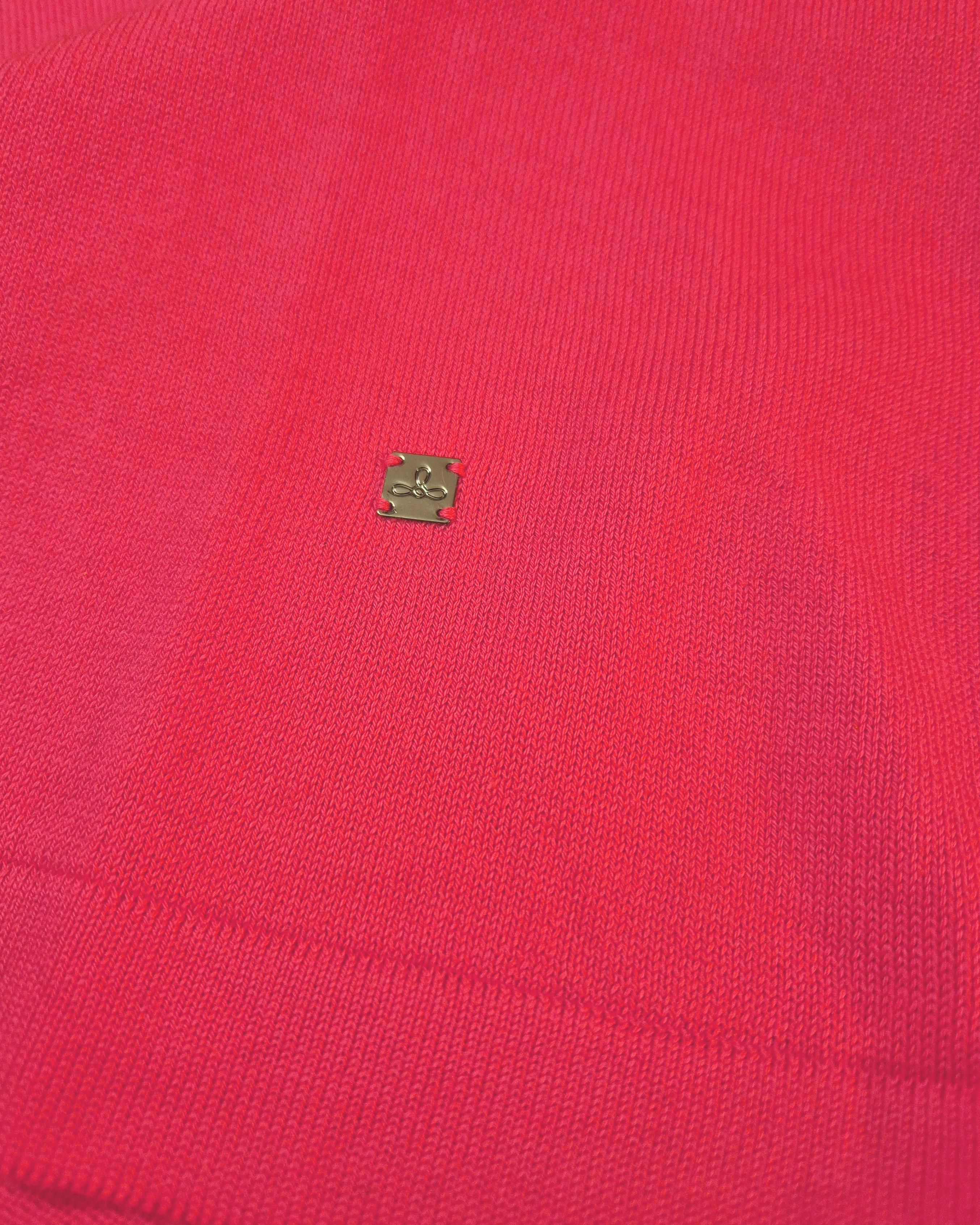 Dettaglio del logo Edua della maglia donna in maglia di cotone rosa corallo con girocollo e profili bianchi sulle maniche