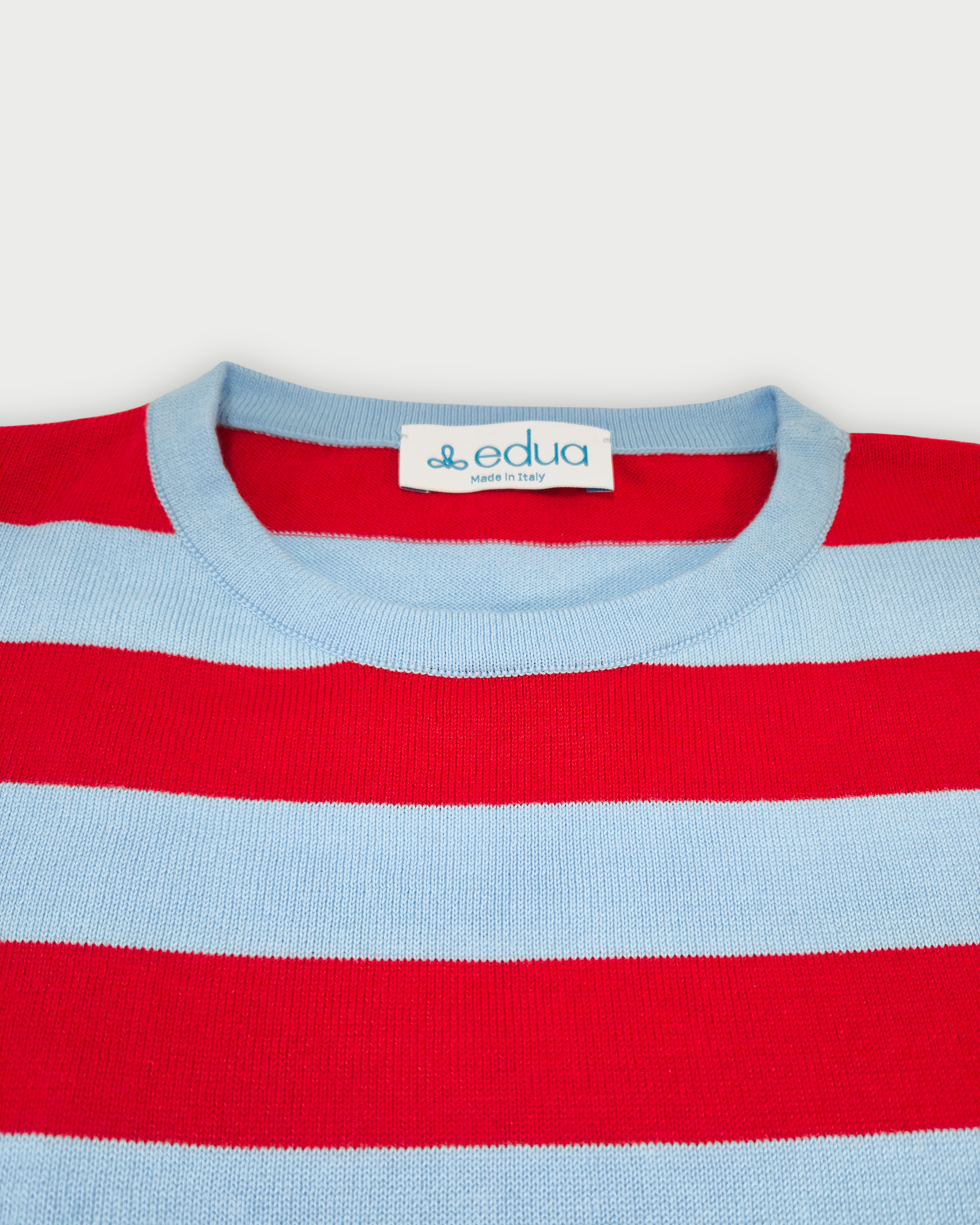 Dettaglio girocollo maglia donna in cotone a righe rosse e celesti su sfondo bianco