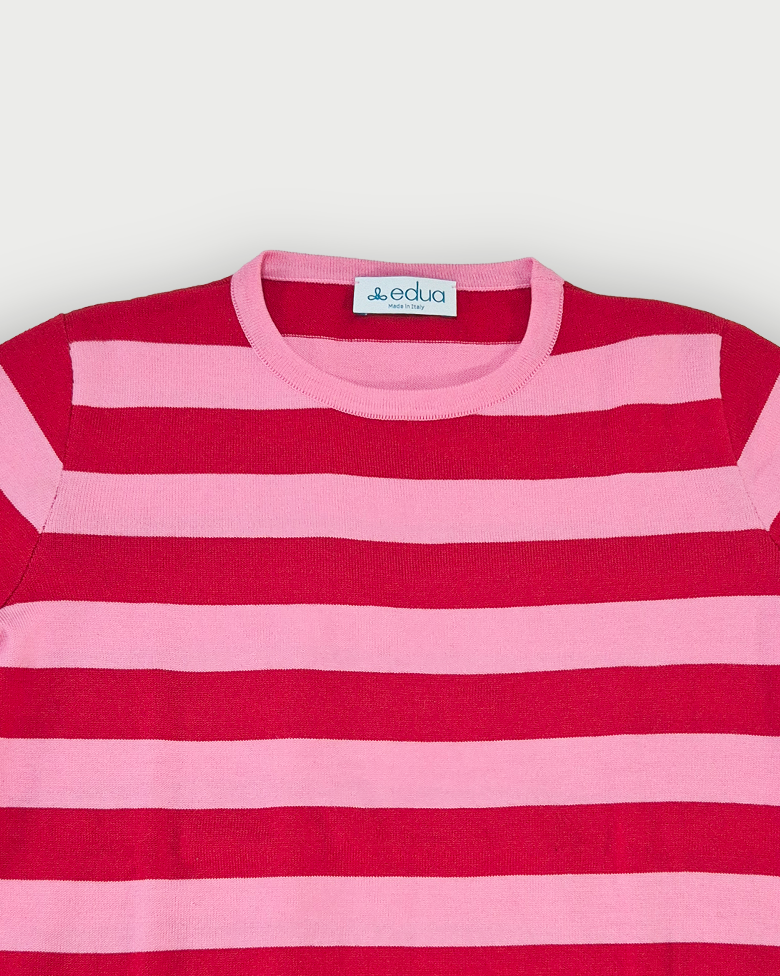 Dettaglio girocollo maglia donna in cotone a righe rosse e rosa su sfondo bianco