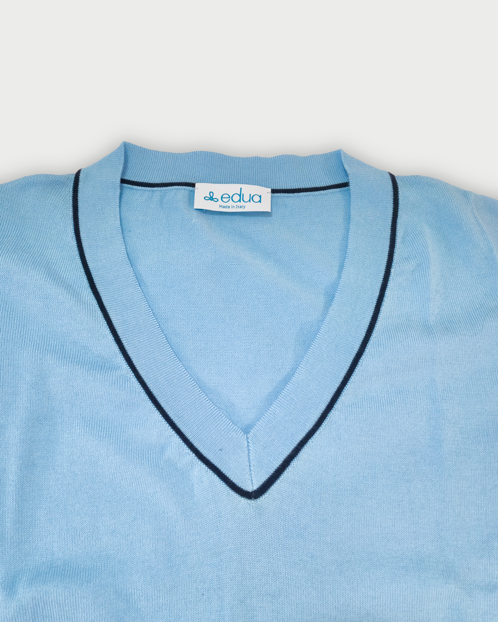 Dettaglio scollo a V maglia donna in maglia di cotone celeste su sfondo bianco