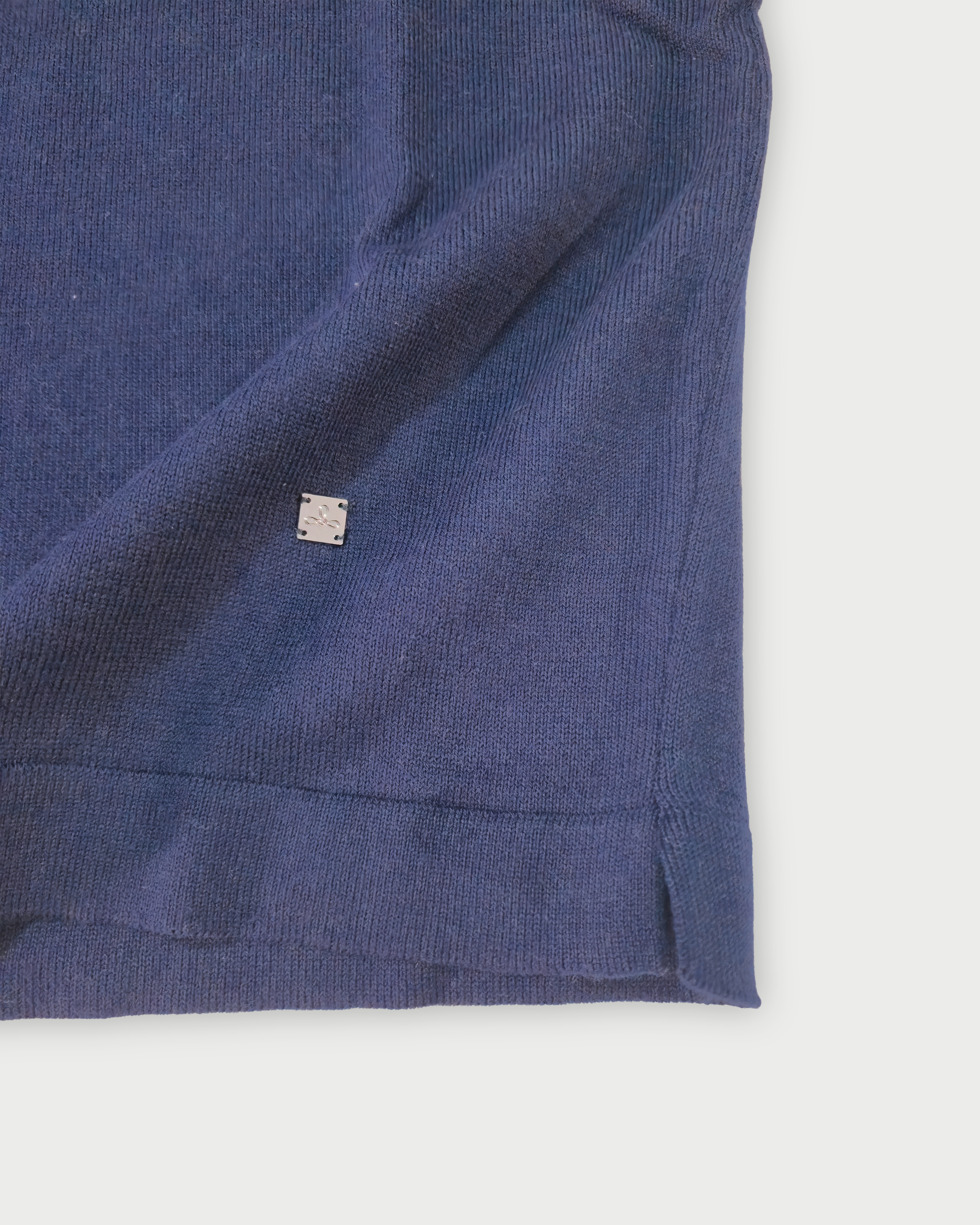 Dettaglio del fondo della polo donna blu con bordi bianchi su sfondo bianco