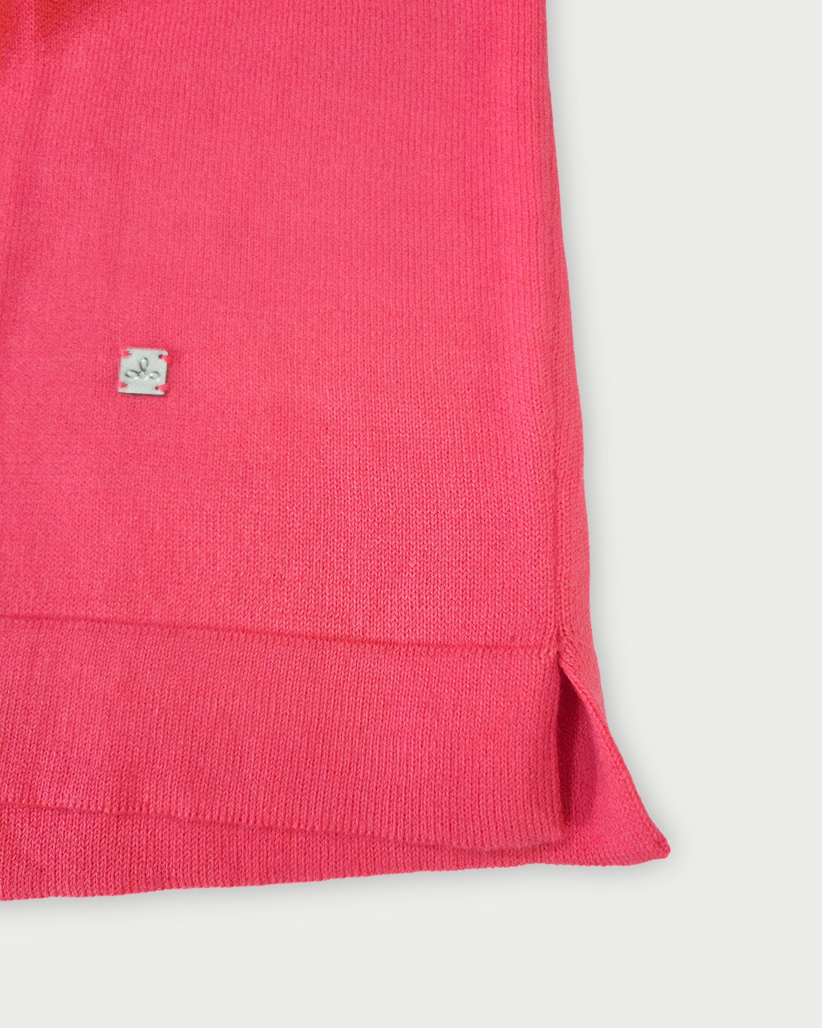 Dettaglio del fondo della polo donna rosa corallo con bordi bianchi su sfondo bianco