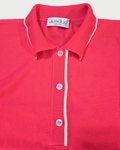 Dettaglio della polo donna over in maglia di cotone rosa corallo con colletto e bordi bianchi su sfondo bianco