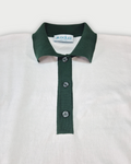 Dettaglio del colletto verde della polo donna over in maglia di cotone bianca su sfondo bianco