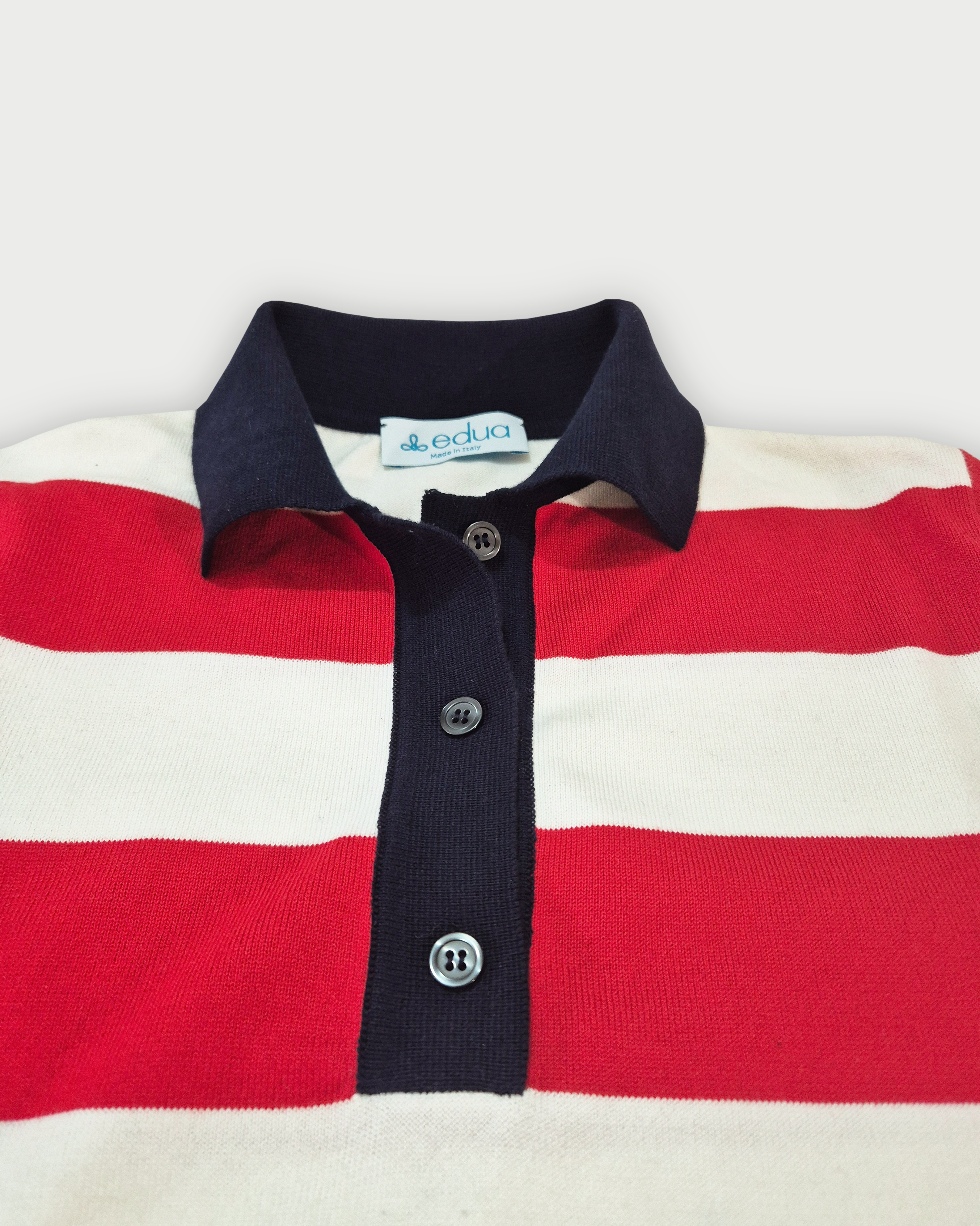 Dettaglio del colletto blu e dell’abbottonatura della polo donna a righe rosse e bianche in maglia di cotone