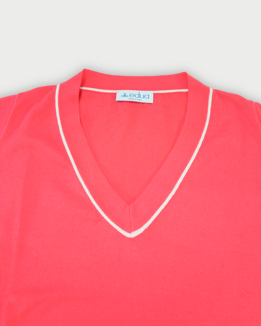 Dettaglio scollo a V maglia donna in maglia di cotone rosa corallo su sfondo bianco