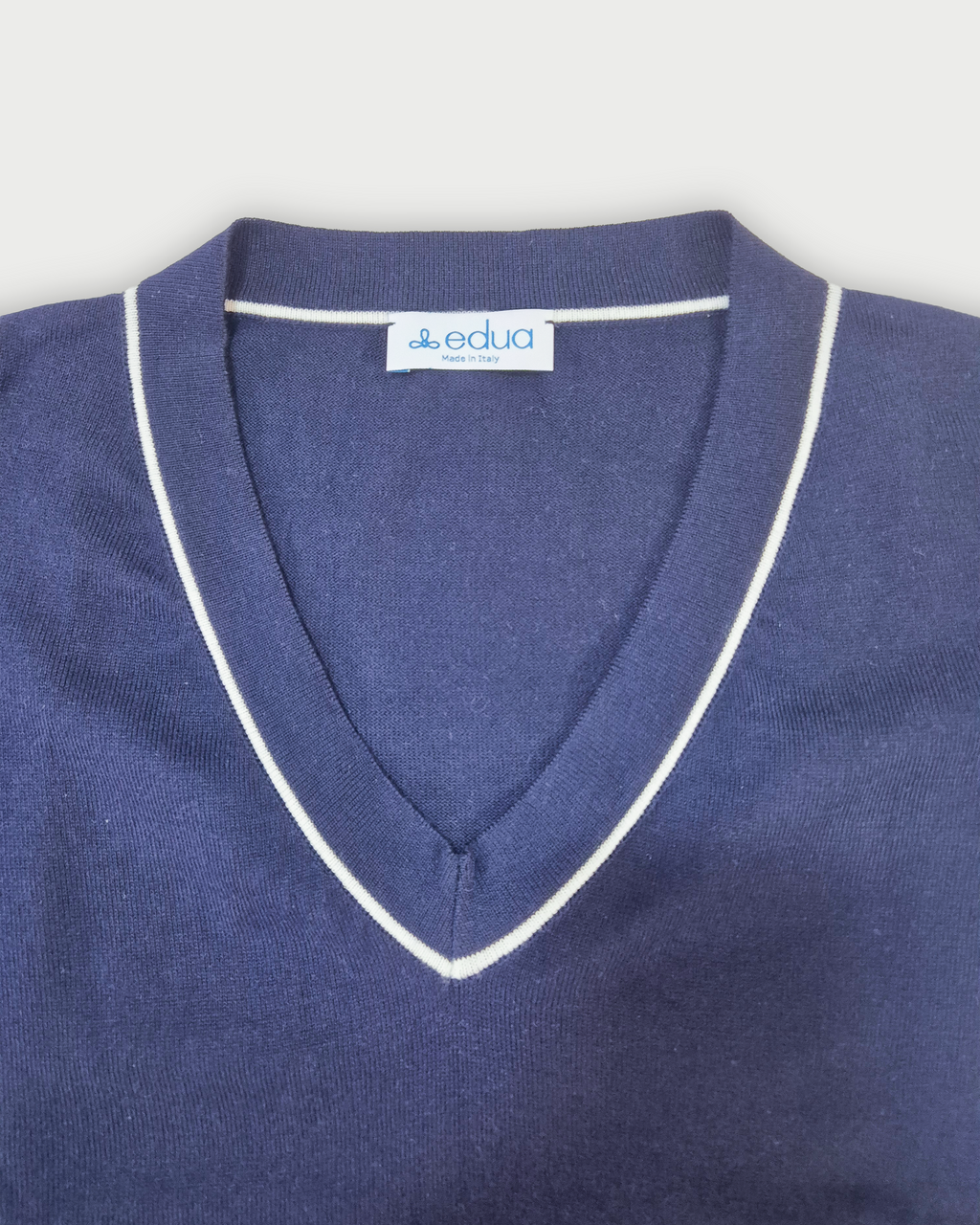 Dettaglio dello scollo a V con profilo bianco della maglia donna in cotone blu su sfondo bianco