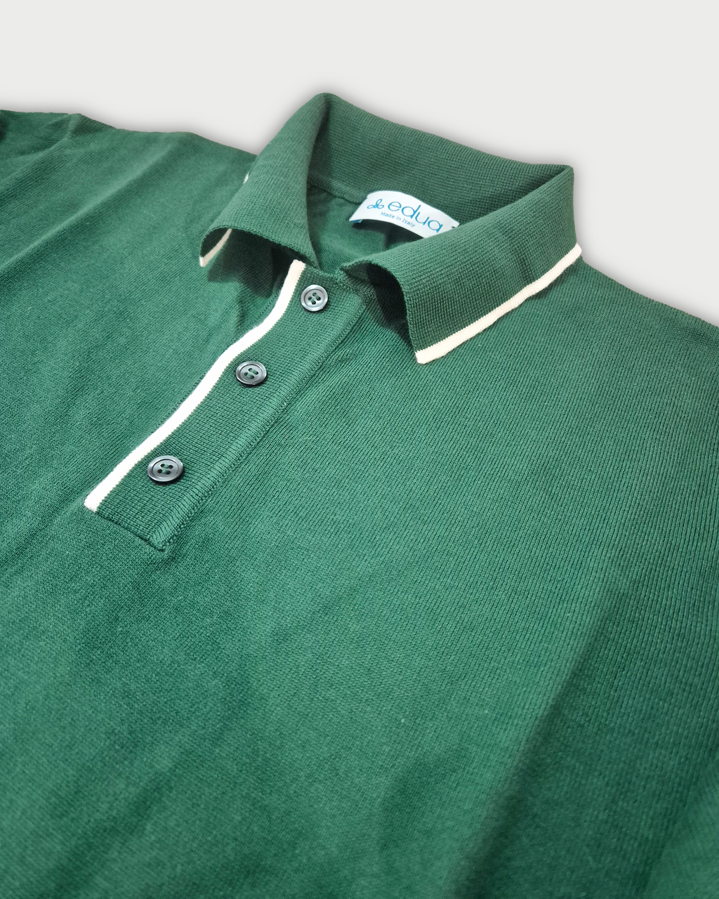 Dettaglio colletto righe bianche polo uomo in maglia di cotone verde su sfondo bianco
