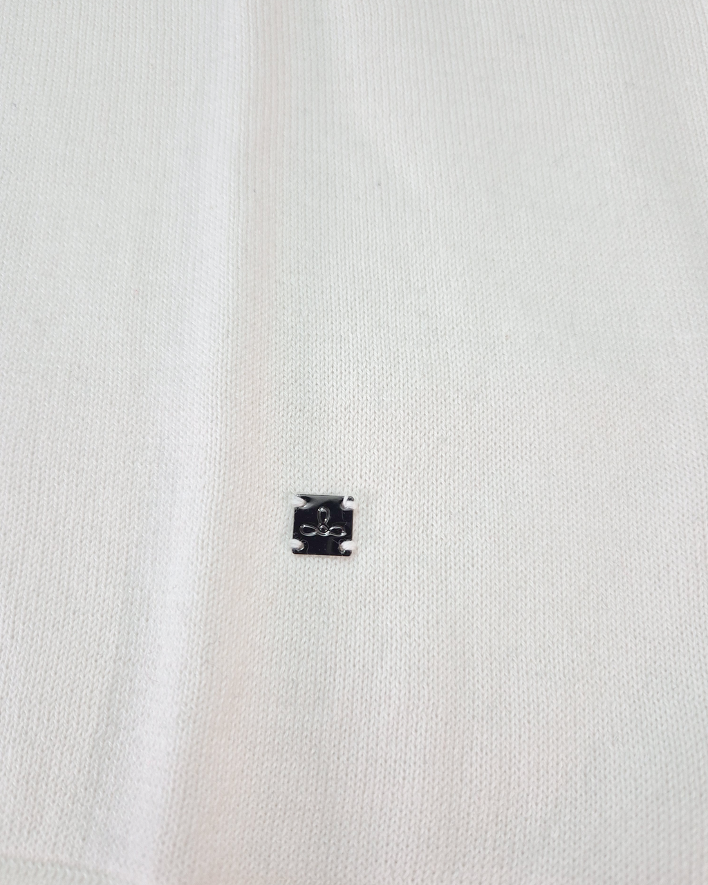 Dettaglio del logo Edua della polo uomo in maglia di cotone ecru con colletto verde