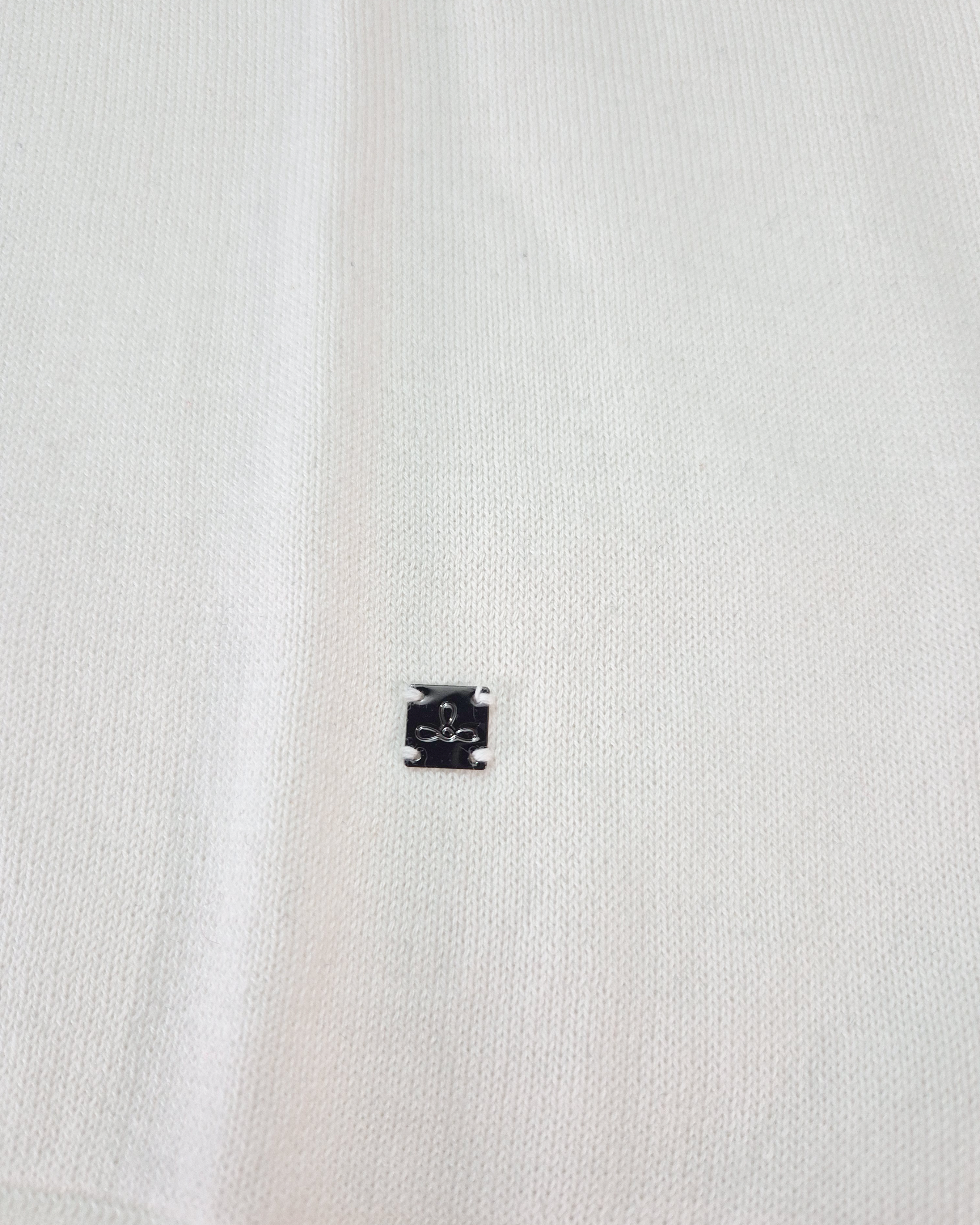 Dettaglio del logo Edua della polo uomo in maglia di cotone ecru con colletto verde