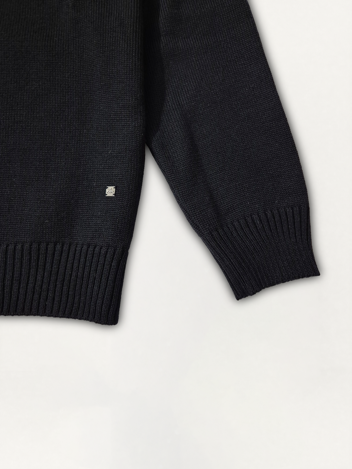 Dettaglio della manica raglan e del logo Edua del maglione girocollo uomo in lana merino colore nero