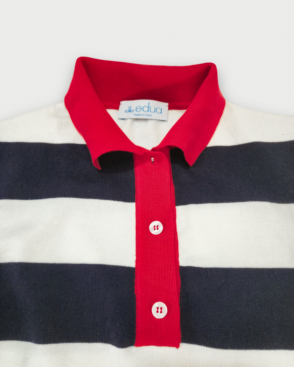 Dettaglio del colletto rosso e dell’abbottonatura della polo donna a righe blu e bianche in maglia di cotone